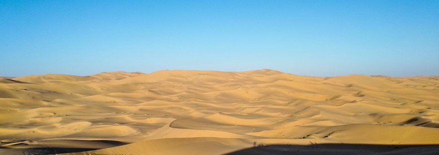 Desert sand under a wide blue sky