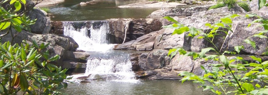 A waterfall spilling over rocks into a deep mountain pool