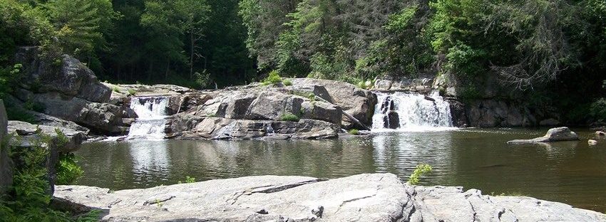 A clear mountain pool below small waterfalls