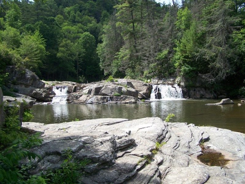 A clear mountain pool below small waterfalls