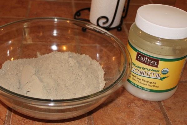 Powdered herbs in a glass bowl beside a jar of coconut oil