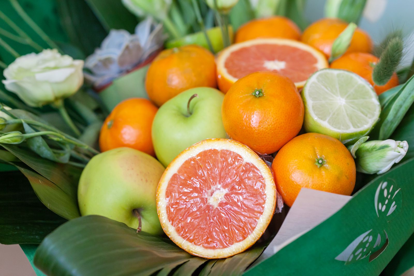 Sliced grapefruit, oranges, limes and green apples on fresh green leaves
