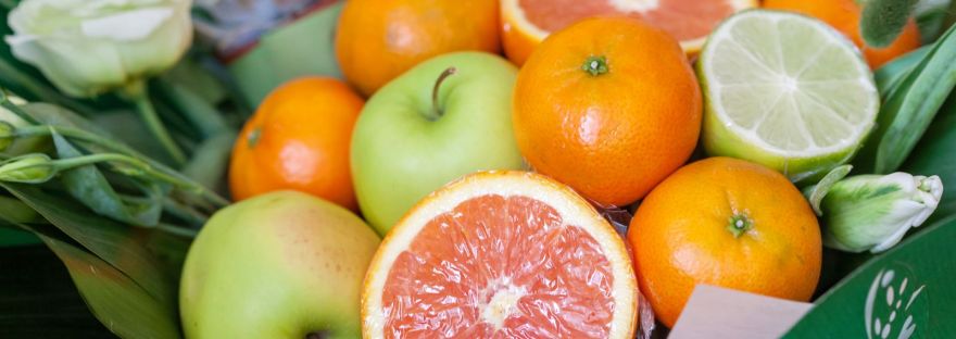 Sliced grapefruit, oranges, limes and green apples on fresh green leaves