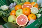 Sliced grapefruit, oranges, limes and green apples on fresh green leaves