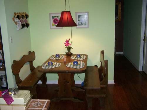 A small wooden kitchen table set with four cups and a pink orchid