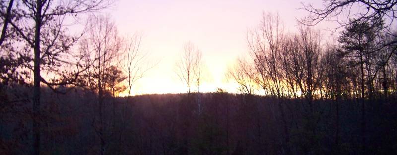 Sunrise breaking over a dark wooded ridge