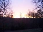 Sunrise breaking over a dark wooded ridge