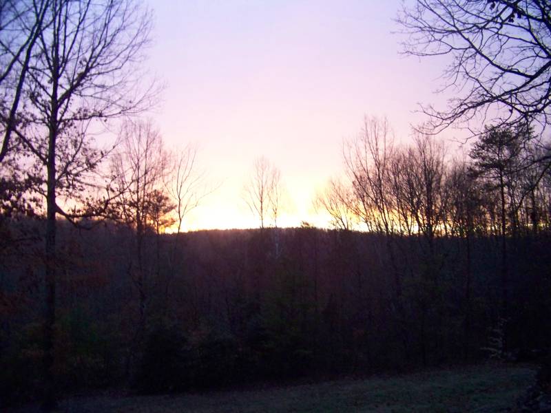 Sunrise breaking over a dark wooded ridge