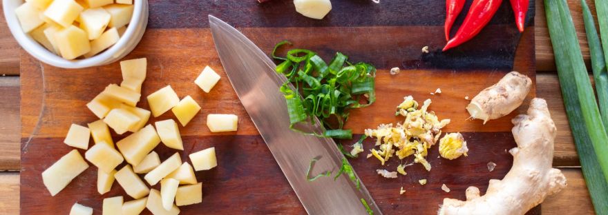Garlic, red hot peppers, ginger root and green onion on a wooden cutting board
