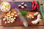 Garlic, red hot peppers, ginger root and green onion on a wooden cutting board